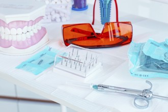 Various instruments, dental models, and hygiene items are laid out on the table in the dental