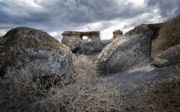 Eroded rock formations with rock tunnels, volcanic landscape with dramatic cloudy skies, Ciudad