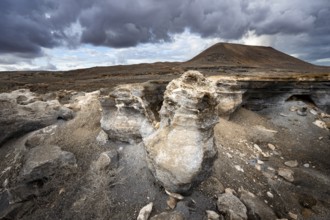 Eroded rock formations in volcanic landscape with dramatic cloudy skies, Ciudad Estratificada or