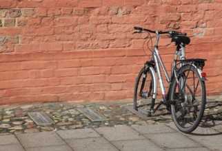 Bicycle parked in front of a red brick wall
