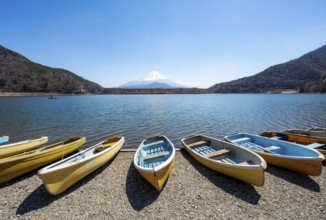 Rowing boats on shore, view across the lake to Mt Fuji volcano, Motosu Lake, Yamanashi Prefecture,