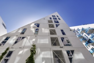 Distinctive white residential complex, turquoise balconies against blue sky, pyramid-shaped