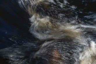 Stream flow with dark water, reflections and turbulences, long exposure, Sweden