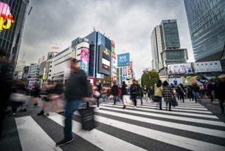 Crowd crossing zebra crossing on a large intersection, motion blur, back modern houses with