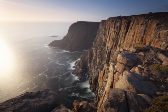 Long exposure shows sunset over the cliffs of Cape Raoul. Golden light hits the sea and colors the