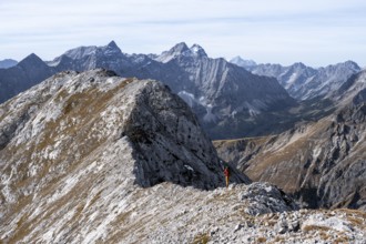 Hikers on the summit ridge of the Gamsjoch, behind rock faces of the Laliderer Spitze, eastern
