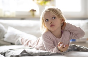 Child, girl, 4 years, blonde, lying on sofa, watching TV, watching television, watching television,