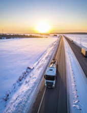 Petrol cargo truck lorry tanker driving on highway hauling oil products at sunrise, wide snowy
