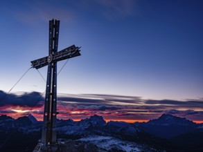 Sassongher summit cross at dawn, in the background Monte Cristallo, Monte Pelmo and Civatta,