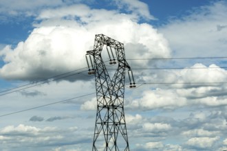 High voltage power lines against a bright blue sky with scattered clouds, Puy de Dome, Auvergne