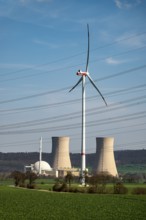 Distant view of the Grohnde nuclear power plant, dominated by a wind turbine, power lines in the