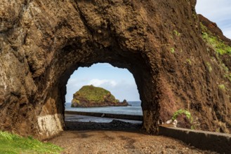 View of the small island of Ilhéu da Ribeira da Janela, Madeira, Portugal, through a tunnel carved