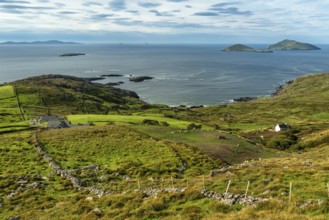 Elevated view over green meadows bordered by natural stone walls and typical cottages to the