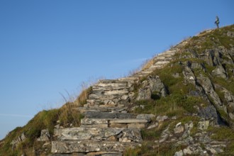 Woman with hiking poles walking up Rørsethornet stone stairs, with 3292 steps one of the longest