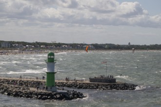 Green and white lighthouse, pier light Westmole in front of lively beach and hotels in the