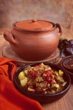 Chanakhi, a Georgian dish. in a clay pot, on a wooden table, stewed meat with vegetables, homemade,