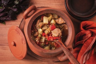 Chanakhi, a Georgian dish. in a clay pot, on a wooden table, stewed meat with vegetables, homemade,