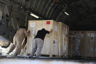 Members of the Qatari Air Force unload humanitarian aid supplies from a transport aircraft at