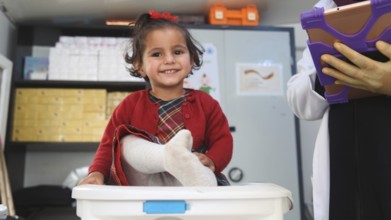 A doctor examining a refugee child for malnutrition in the camp using weight and height measurement