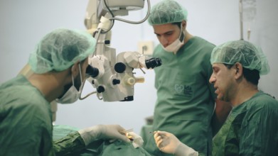 Several doctors performing a complex surgical operation inside an operating room for a displaced