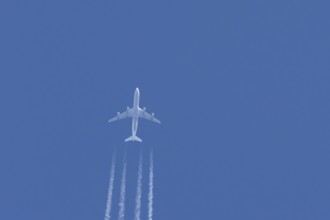 Airbus A340-300 jet aircraft of Lufthansa airlines in flight in a blue sky with vapour trails or