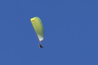 Paraglider flying in a blue sky, England, United Kingdom