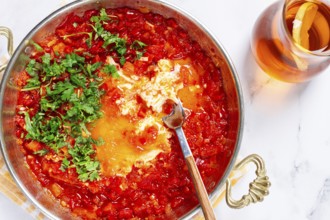 Traditional Turkish dish, scrambled eggs with tomatoes, Menemen, with herbs, in a frying pan,