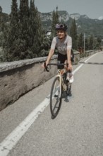 Young woman riding a racing bike on Lake Garda. Sunny weather and dolce vita