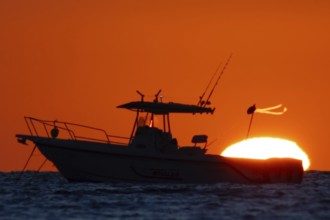 The sun rises behind a boat on the Costa Rei, a coastal stretch of the Italian Mediterranean island