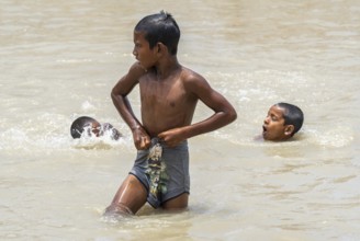 Children bathe in the Brahmaputra River to seek relief from the intense summer heat in Guwahati,