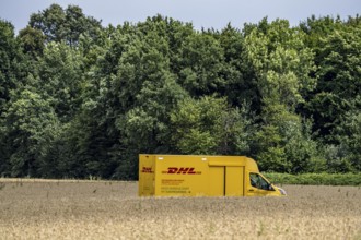 DHL parcel van, electric vehicle, on the way to a customer, rural, driving along a dirt track