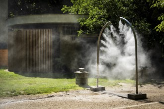 A mobile spray arch sprays fine water mist in a park in Bratislava, Slovakia