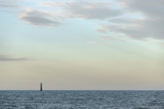 A lighthouse rises from the gentle waves of the ocean, surrounded by a tranquil seascape. Soft