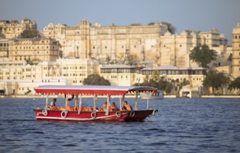 Excursion boat on Lake Pichola, behind the City Palace in the evening light, Udaipur, Rajasthan,