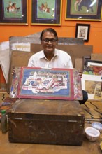 Miniature painter, 50 years old, shows a picture of the royal city palace in his studio, Udaipur,