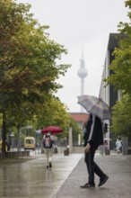 People walk with umbrellas through the government district in Berlin, 21.07.2025