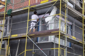 Construction workers insulate a house facade