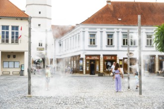 Water mist system in the city centre of Trencin, children use the refreshment in the summer heat,