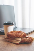 Simits with coffee on a wooden table, with a laptop, in a cozy working environment, snack,