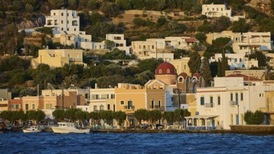 Picturesque waterside village with traditional architecture and a church in hilly terrain, Agia