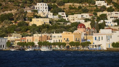 Colourful houses of a coastal village with hills in the background and water in the foreground,