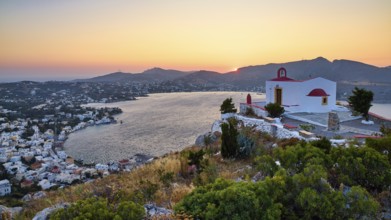 Profitis Ilias Church, A red-roofed church overlooks the bayside village at sunset, creating an