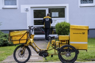 Postman, Deutsche Post, distributes the mail in an apartment building, electric tricycle, North
