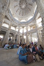 Indian woman praying between the white marble pillars in the Adinath temple in Ranakpur, Jain