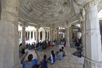 Indian woman praying between the white marble pillars in the Adinath temple in Ranakpur, Jain