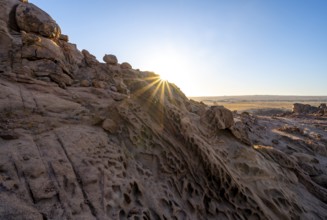Eroded rock formations at sunrise with sun star, Erongo, Damaraland, Namibia