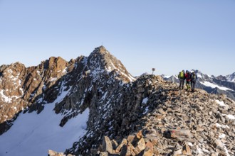 Mountaineer on a ridge, in the background summit Wilder Freiger with summit cross, Stubai Alps,
