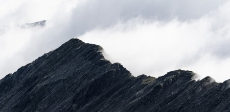 Mountain ridge with summit Zunderspitz and summit cross, cloudy, Stubai Alps, near Ridnaun, South