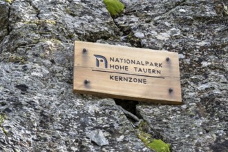 Wooden sign on rock, inscription Hohe Tauern National Park core zone, Schober group, Hohe Tauern
