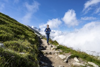 Mountaineer on a hiking trail, inversion weather situation with clouds in the valley, Chamonix,